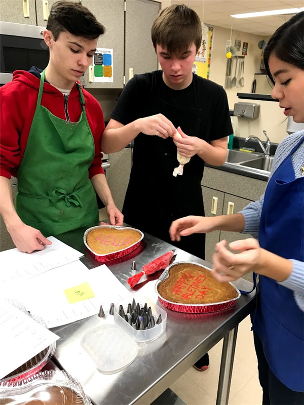 Students baking heart shaped cakes.